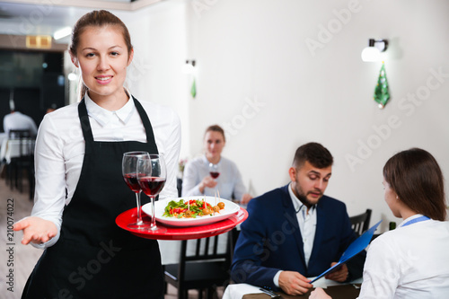 Portrait of welcoming female waiter who is standing in restaurante