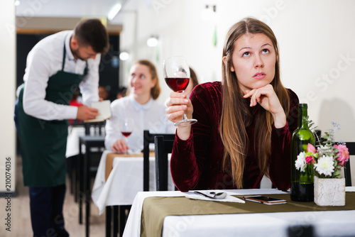 Elegant upset woman is expecting man for dinner in luxury restaurante