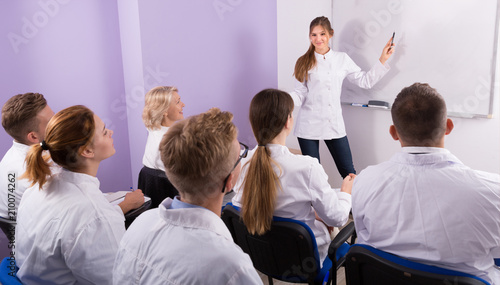 Woman medical student lecturing near whiteboard in auditorium