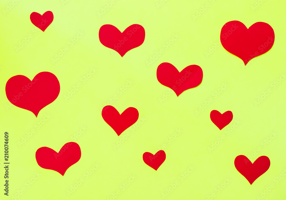 Red paper hearts on a yellow-green paper background Red paper hearts on a yellow-green paper background