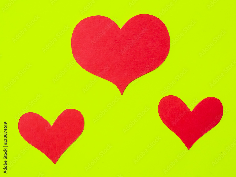 Red paper hearts on a yellow-green paper background Red paper hearts on a yellow-green paper background