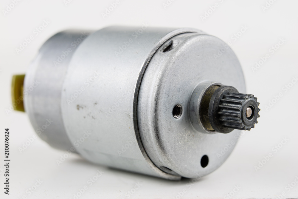 Small electric motor on a white workshop table. Electric drive used in small electrical devices. Small electric motor on a white workshop table. Electric drive used in small electrical devices.