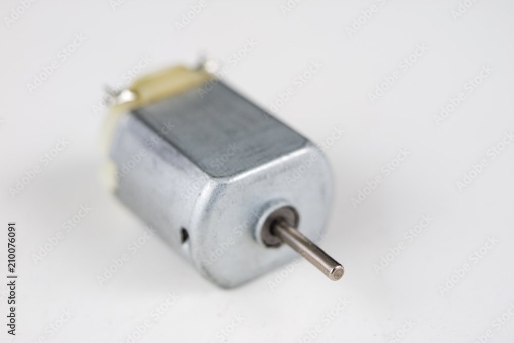 Small electric motor on a white workshop table. Electric drive used in small electrical devices. Small electric motor on a white workshop table. Electric drive used in small electrical devices.