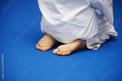 Photography A boy in a white kimono sits on a blue tatami during a workout