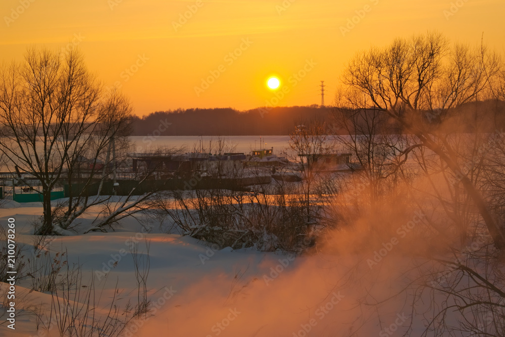 The shore of the Kostroma River and the river in winter at sunset.