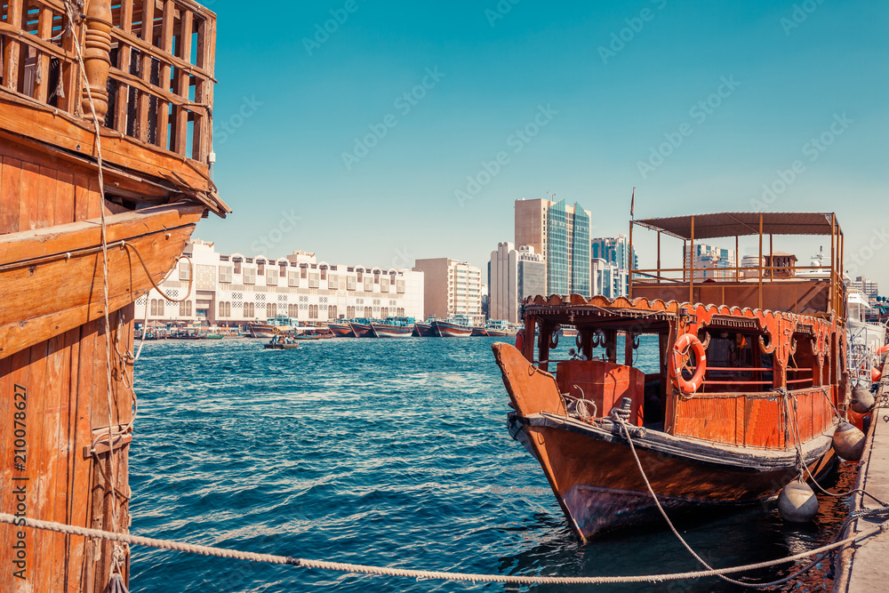 Fototapeta premium Skyline view of Dubai Creek with traditional boats and piers. Sunny summer day. Famous tourist destination in UAE.