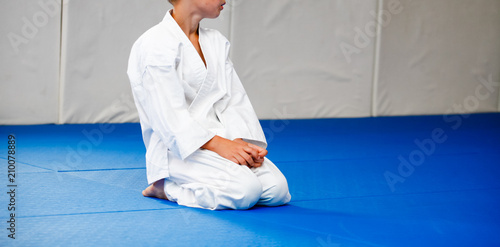 Photography A boy in a white kimono sits on a blue tatami during a workout.