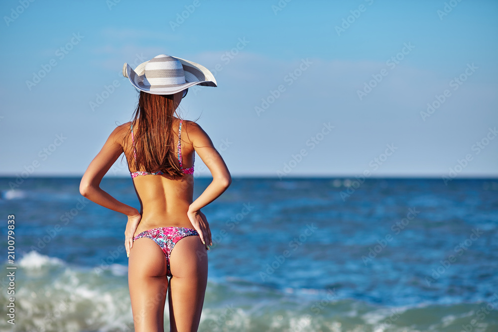 Sexy back of a beautiful woman in bikini on sea background. Sexy buttocks. Exotic country travel and rest concept.
