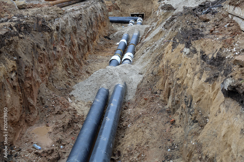 Black steel pipes of the water pipeline in the excavated earth ditch
