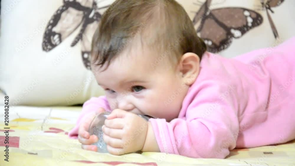 Cute baby girl showing tongue, the baby crawls on the couch, sucks a pacifier, a bottle, baby food, gets up from the hand, a child up to a year, todler Cute baby girl showing tongue, the baby crawls on the couch, sucks a pacifier, a bottle, baby food, gets up from the hand, a child up to a year, todler