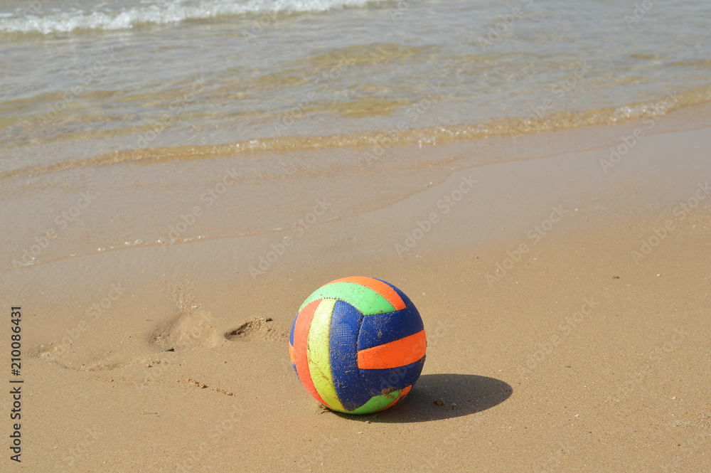 Ball on the sandy beach of sunny relaxing coastline, daytime seaside nature idyllic background