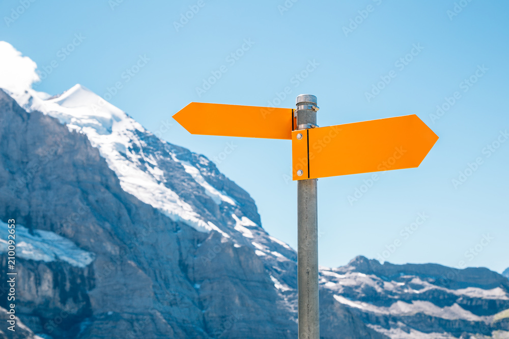 Arrow direction sign with snowy mountain