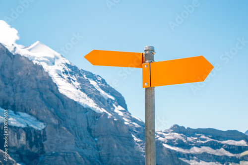Arrow direction sign with snowy mountain
