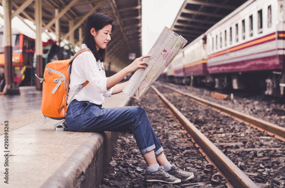 Girl wearing backpack holding map, waiting for a train. Traveling in Bangkok Thailand. Travel concept Girl wearing backpack holding map, waiting for a train. Traveling in Bangkok Thailand. Travel concept