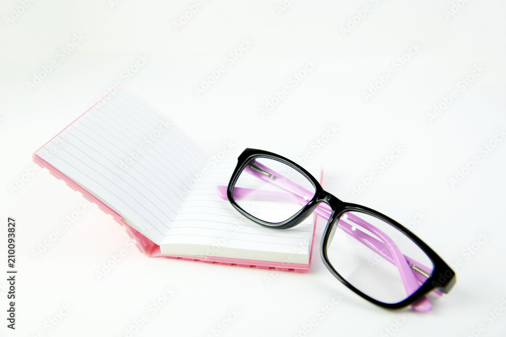 Black glasses and book pink on white background Black glasses and book pink on white background