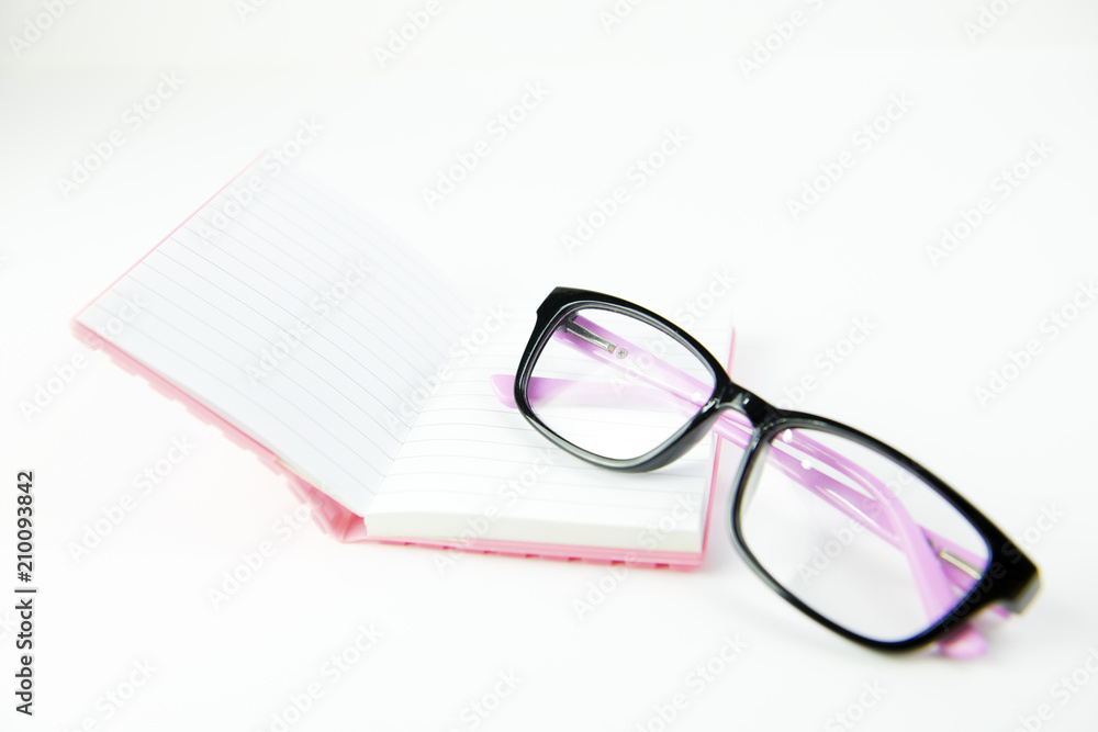 Black glasses and book pink on white background Black glasses and book pink on white background