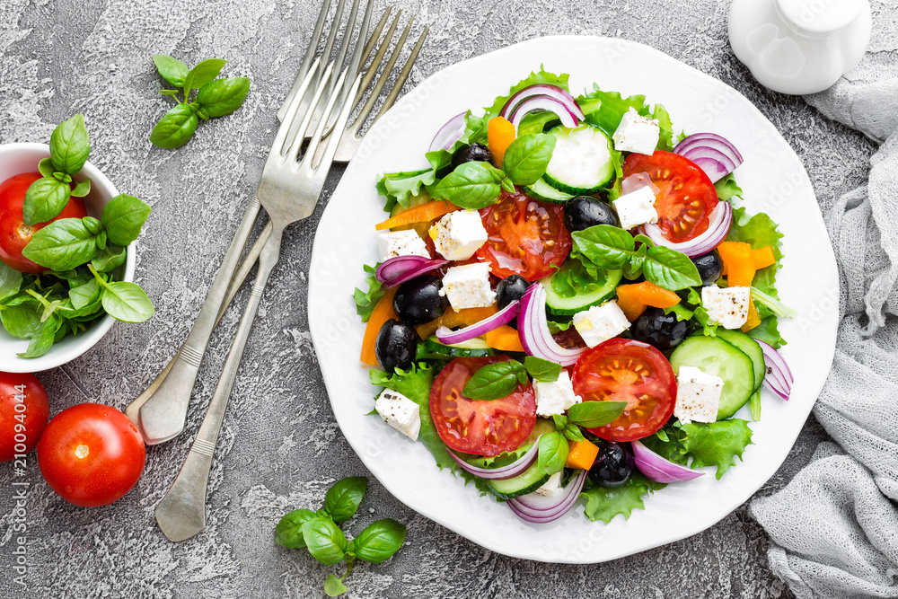 Greek salad. Fresh vegetable salad with tomato, onion, cucumbers, pepper, olives, lettuce and feta cheese. Greek salad on plate Greek salad. Fresh vegetable salad with tomato, onion, cucumbers, pepper, olives, lettuce and feta cheese. Greek salad on plate