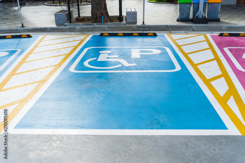 International handicapped (wheelchair) or Disabled parking symbol painted in bright blue on parking space.