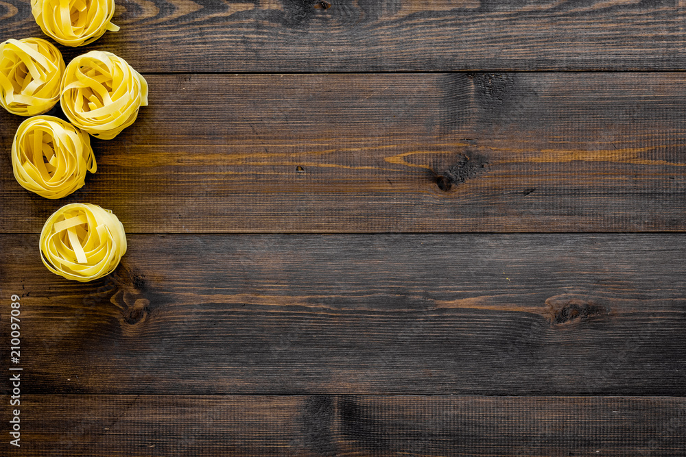 Uncooked pasta fettuccine frame on dark wooden background top view copy space Uncooked pasta fettuccine frame on dark wooden background top view copy space