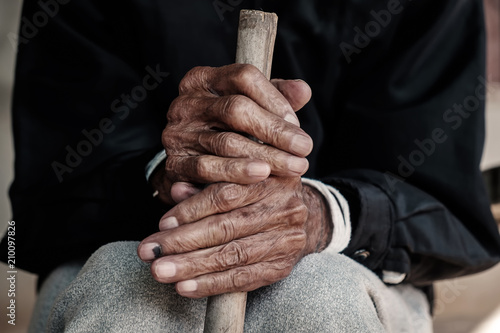 Asian old man sitting with his hands on a walking stick © Nuttapong punna