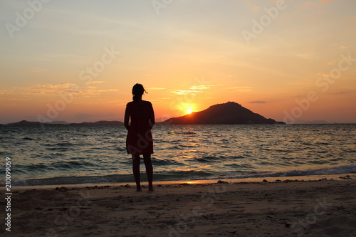 Woman silhouetted in front of sunset at the beach