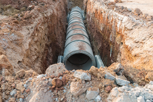 Row of concrete drainage pipe under earth near the construction site. photo