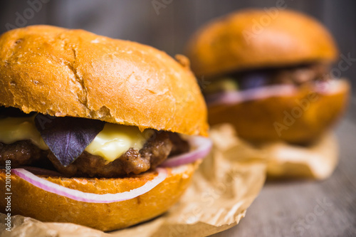 Tasty burger with basil on the rustic wooden background. Selective focus. Shallow depth of field.