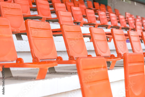 Row of orange empty chairs stadium seats in stadium