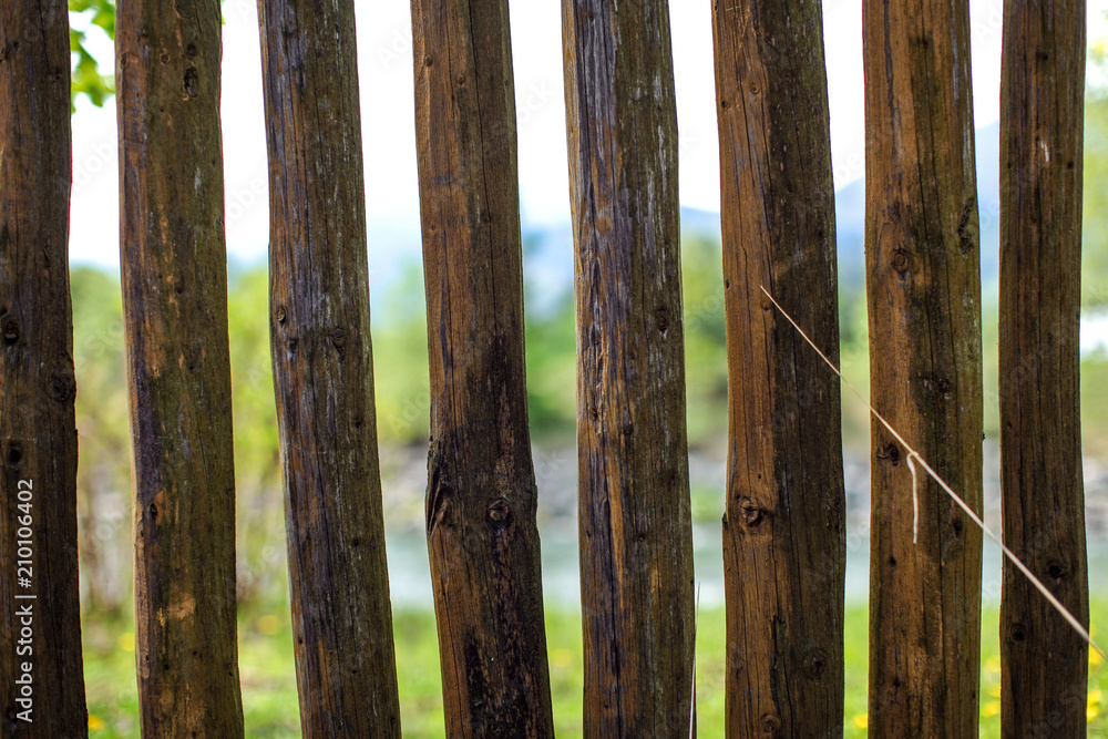 Close up photo - old wooden fence posts poles, with blurred spring country and river in background. Close up photo - old wooden fence posts poles, with blurred spring country and river in background.