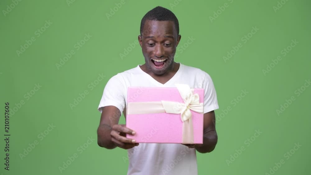 Young happy African man looking surprised while opening gift box Young happy African man looking surprised while opening gift box