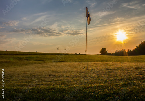 Golf course with two balls near flag in sunrise