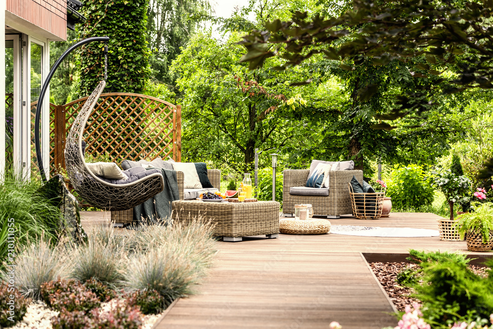 Φωτογραφία Single swing and garden furniture set on a wooden terrace in a green garden with