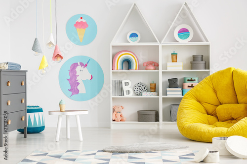 Yellow pouf in colorful child's room interior with lamps and posters