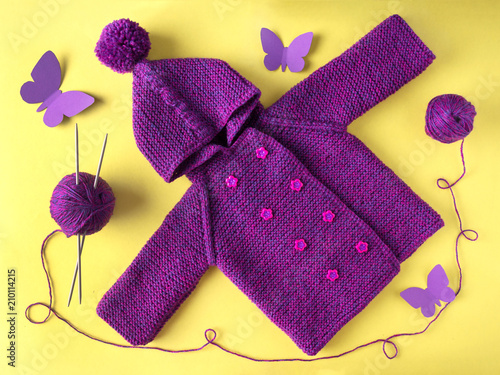 Knitted baby jacket with hood.