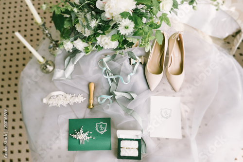Elegant wedding bouquet with a ribbon, wedding invitation, rings and bridal shoes on tissue 