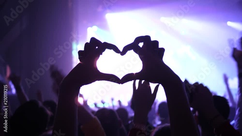 Making heart silhouette young fan spectator girl fingers sway hand enjoy music concert in a crowd photo