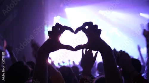Making heart silhouette young fan spectator girl fingers sway hand enjoy music concert in a crowd