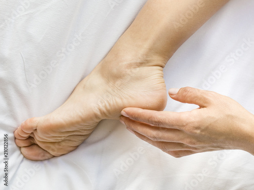 Woman applying cream onto her feet, closeup.