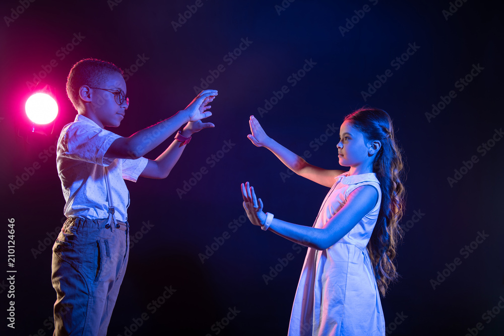 Imaginary world. Serious lovely kind boy and a girl standing face to face and pressing imaginary buttons Imaginary world. Serious lovely kind boy and a girl standing face to face and pressing imaginary buttons