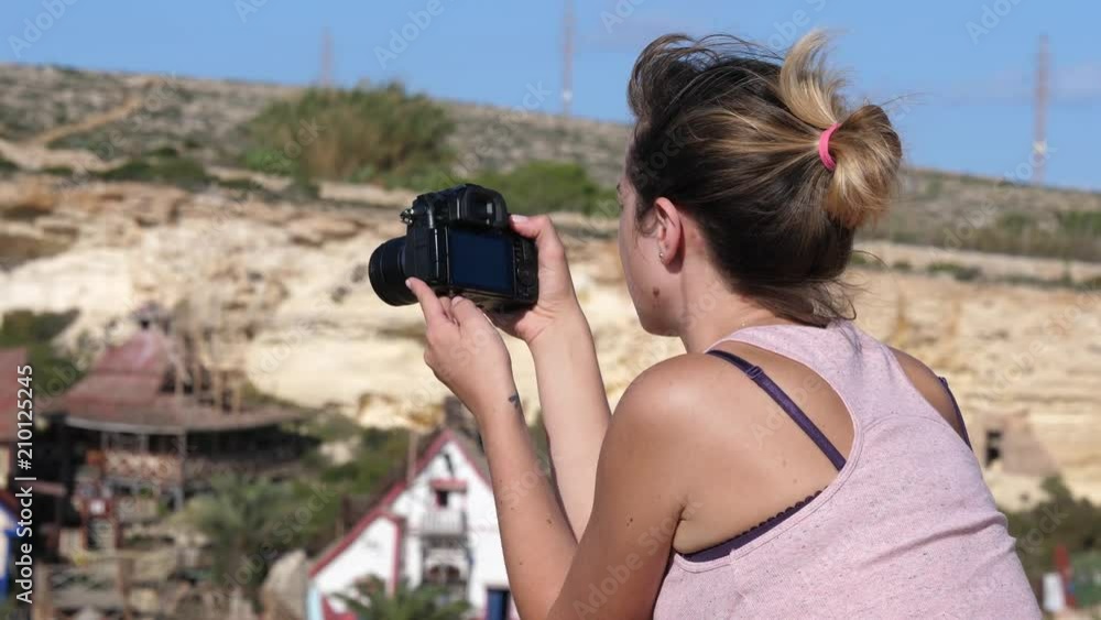 Young woman tourist takes pictures with photo camera traveling to Malta Young woman tourist takes pictures with photo camera traveling to Malta