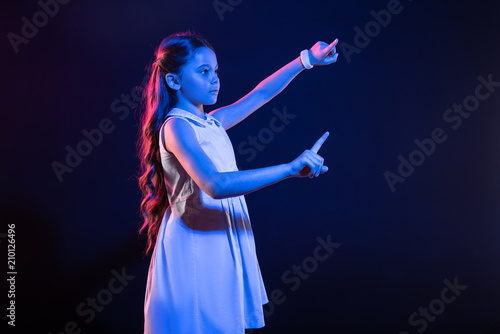 My concentration. Unsmiling dark-haired girl pressing imaginary buttons and wearing a lovely dress