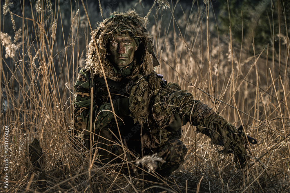 Camouflaged soldier during patrol in sunny day