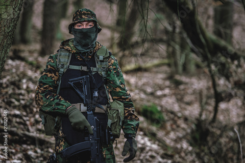 Airsoft player in eastern uniform during playtime in forest