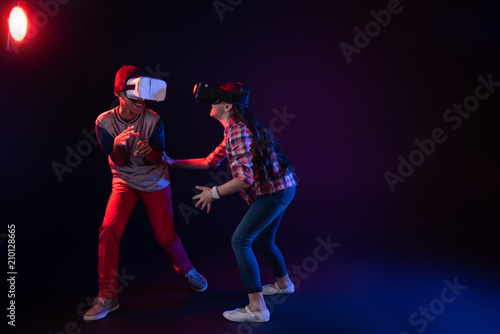 Happy day. Joyful cute girl and a boy wearing VR headsets and playing an interesting game