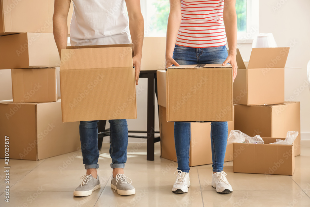 Young couple with boxes indoors. Moving into new house Young couple with boxes indoors. Moving into new house