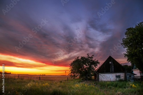 Sunset in the countryside. Incredibly beautiful sky with red clouds and a small rural house. 