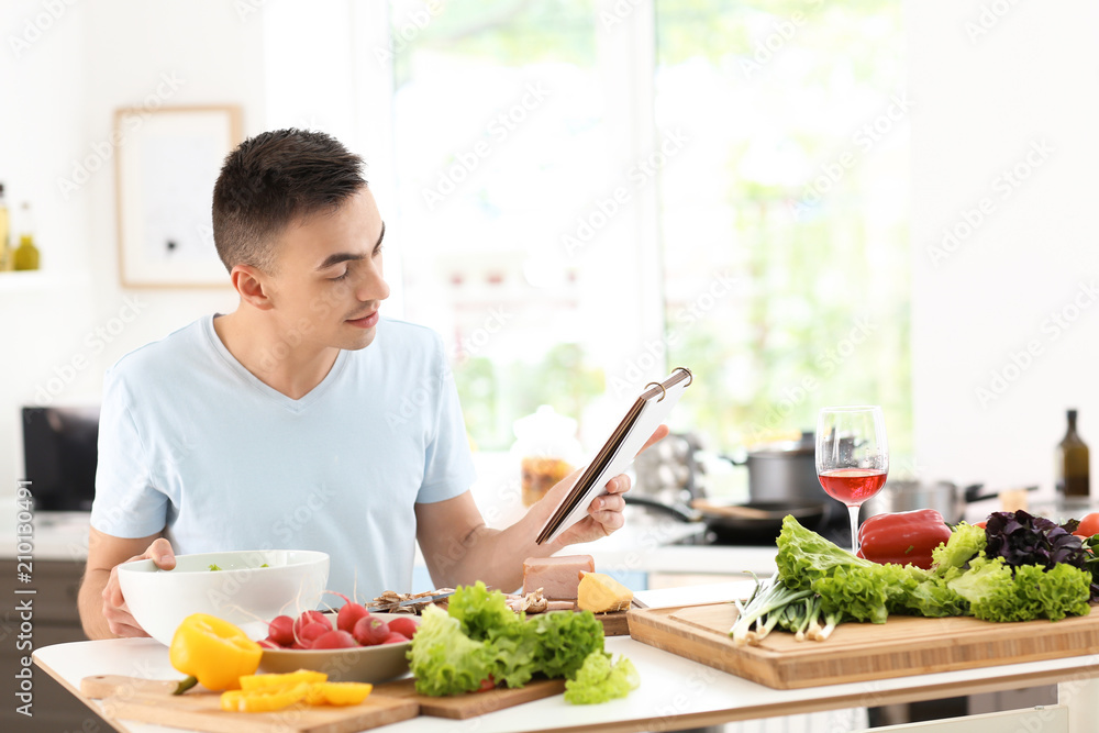 Young man reading recipe book in kitchen Young man reading recipe book in kitchen
