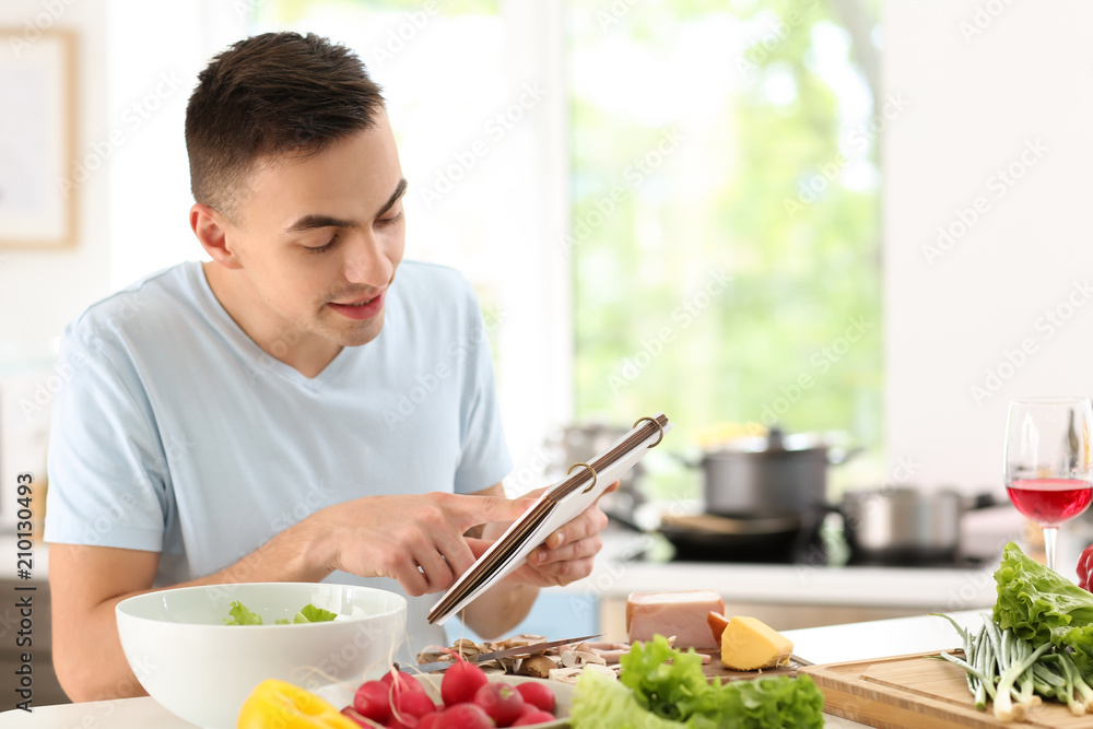 Young man reading recipe book in kitchen Young man reading recipe book in kitchen
