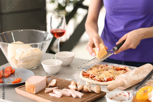 Young woman preparing pizza in kitchen