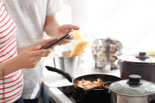 Young couple with tablet reading PC recipes in kitchen